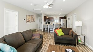 A living room with a brown sofa, a coffee table, and a kitchen in the background.