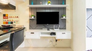 Eine moderne Küche mit integriertem Fernseher, weißen Schränken und einem Essbereich mit einem schwarzen Stuhl.