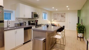 Een moderne keuken met witte kasten, roestvrijstalen apparatuur en een centraal eiland met barkrukken.