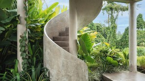 A spiral staircase surrounded by lush tropical plants. - Kuze House by Alfred in Bali (Canggu)