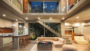 A modern interior with a kitchen, dining area, and living room, featuring a staircase connecting two floors. - Kuze House by Alfred in Bali (Canggu)