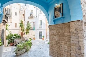A courtyard with a blue archway, potted plants, and a stone wall. - Emma Art & Wine - Historic Townhouse (Bari)