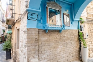 Ein Gebäude mit blauer Fassade, einem Schild mit der Aufschrift 'Corte Carducci' und einem Fenster mit Blick auf die Straße.
