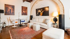A living room with a white sofa, a red rug, a coffee table, and a fireplace. - Emma  Art & Wine - Historic Townhouse (Bari)