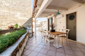 A patio with a wooden table and chairs, a door, and a stone wall. - Emma Art & Wine - Historic Townhouse (Bari)