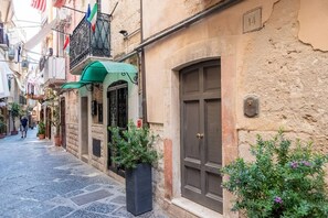 Una calle estrecha con edificios, un toldo verde y una puerta con placa numérica.