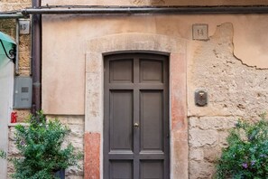 A building with a dark brown door, numbered 14, and a gas meter to the left.