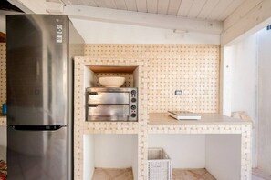 Una cocina compacta con un refrigerador de acero inoxidable, un horno empotrado y un microondas.