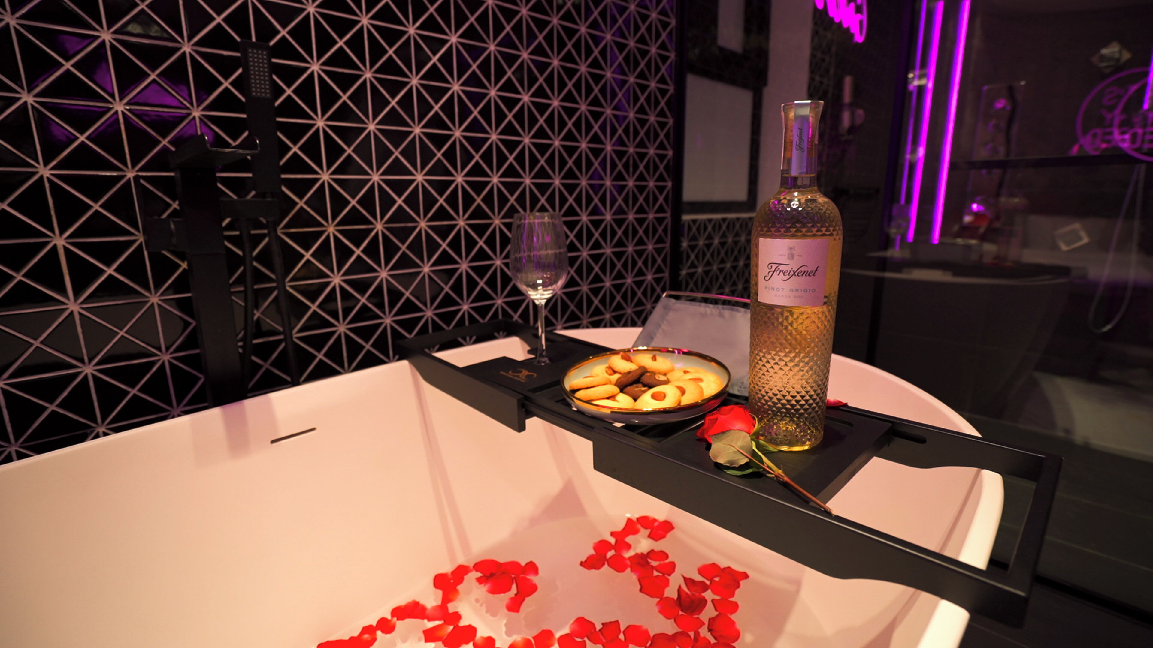 A table with a bottle of wine, a glass, and a plate of cookies.