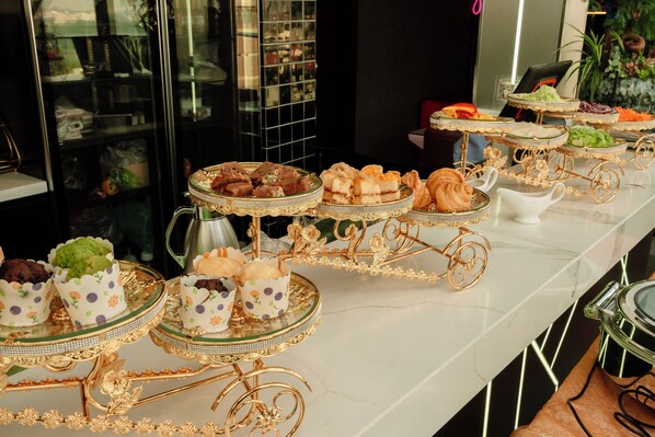 A buffet table with various food items and decorative gold stands. - X-Digital Hotel (Kinh Bac)