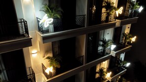 A multi-story building with balconies, each adorned with potted plants and illuminated signs. - X-Digital Hotel (Kinh Bac)