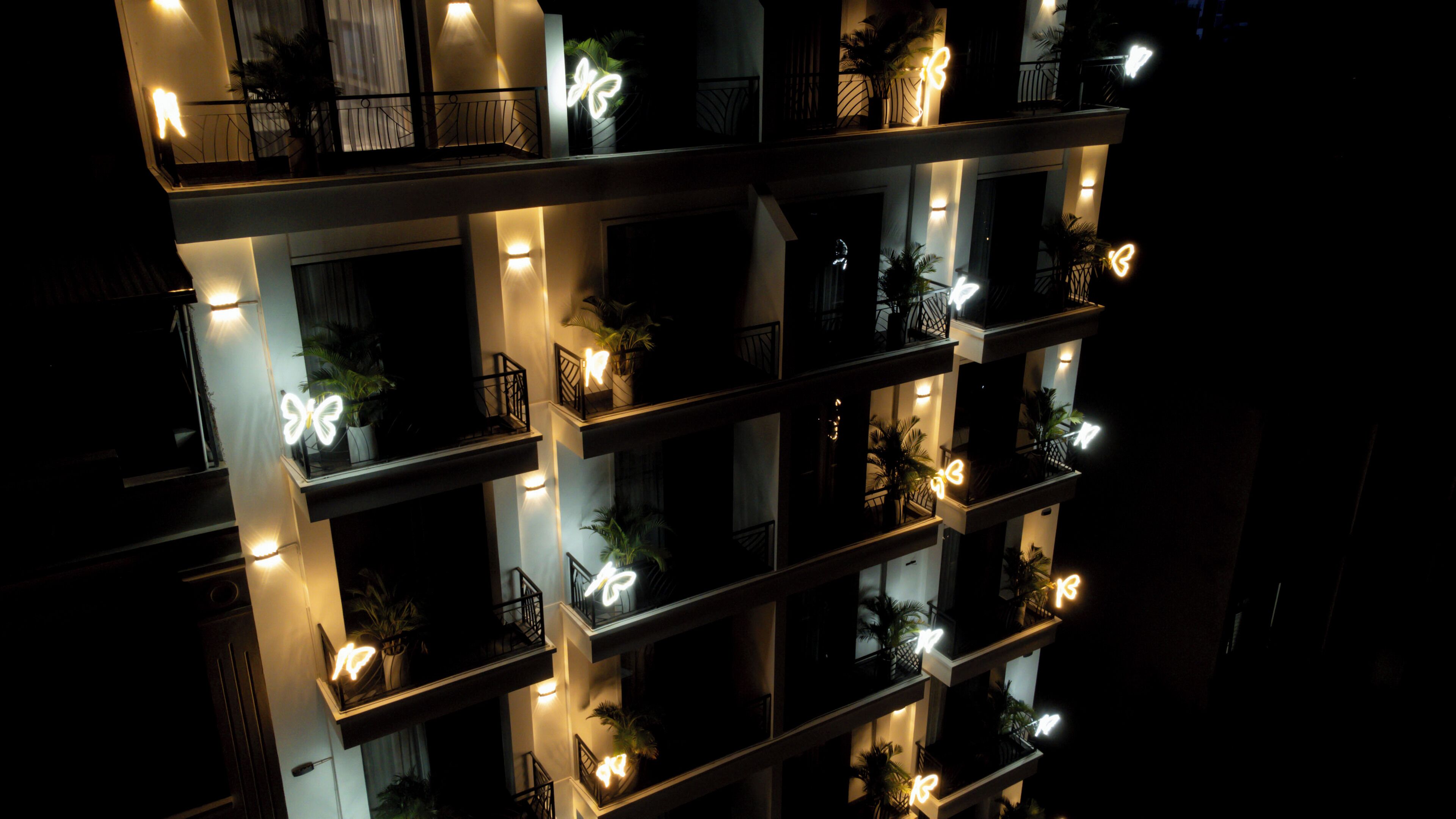 Un immeuble à plusieurs étages doté de balcons, chacun étant éclairé par une lumière douce.