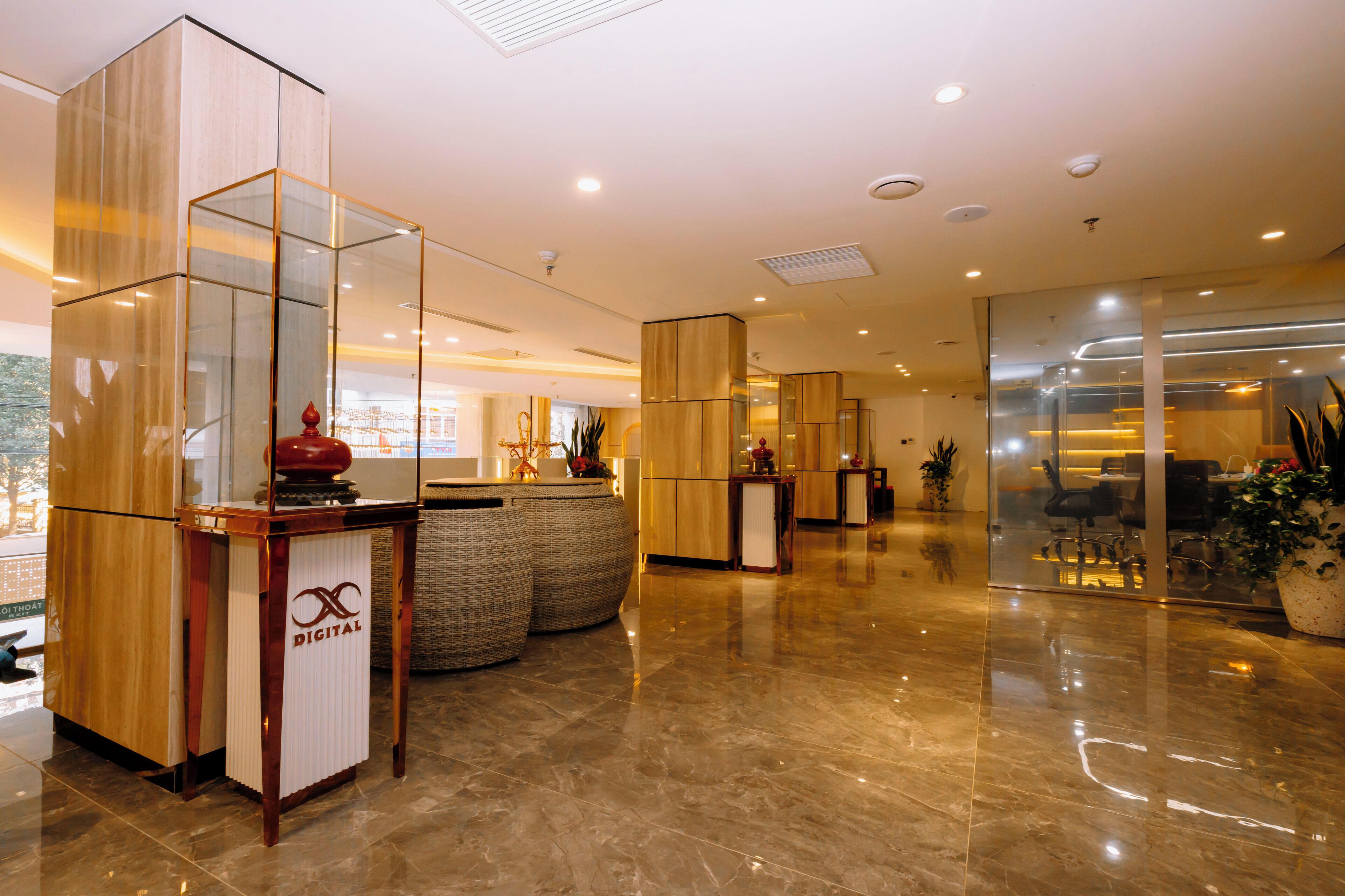 A modern lobby with a reception desk, seating area, and glass partitions.