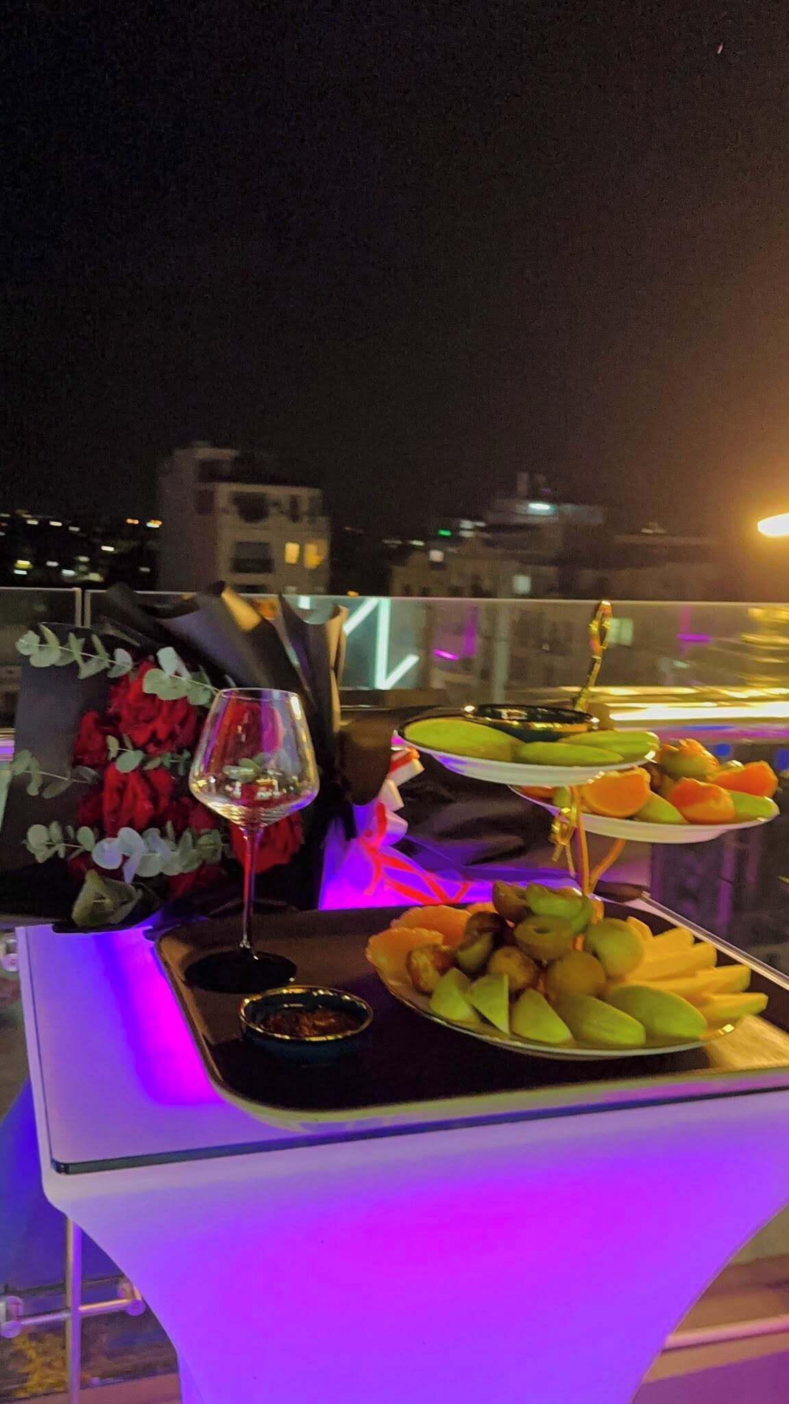 A table set with a wine glass, a plate of fruit, and a decorative item.