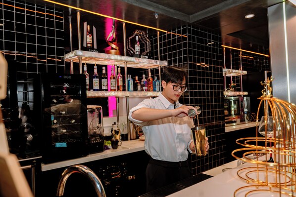 A bar area with shelves of liquor bottles, a coffee machine, and a gold decorative structure. - X-Digital Hotel (Kinh Bac)