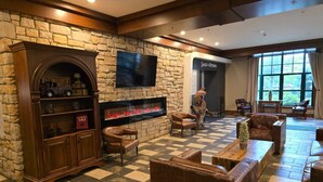 A lobby with a stone wall, a fireplace, leather furniture, and a flat-screen TV.