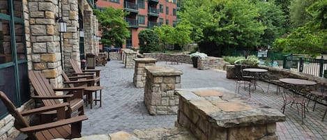 An outdoor patio with stone walls, wooden chairs, and tables.