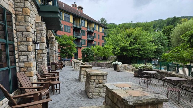 An outdoor patio area with stone walls, wooden chairs, and tables.