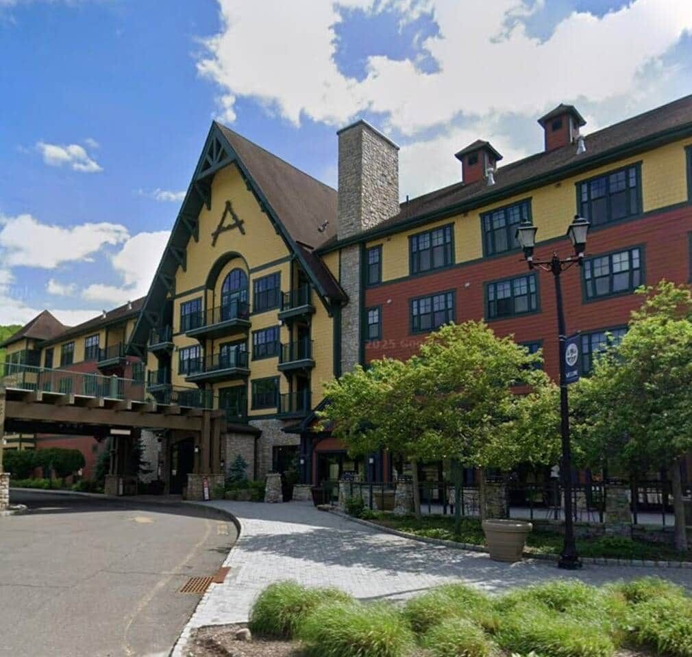 A multi-story building with a prominent clock tower, a covered walkway, and a landscaped entrance area.