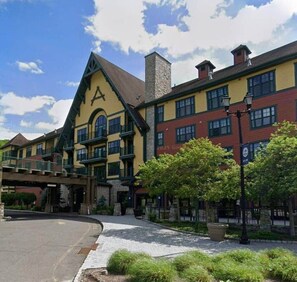 A multi-story building with a prominent clock tower, a covered walkway, and a landscaped entrance area.