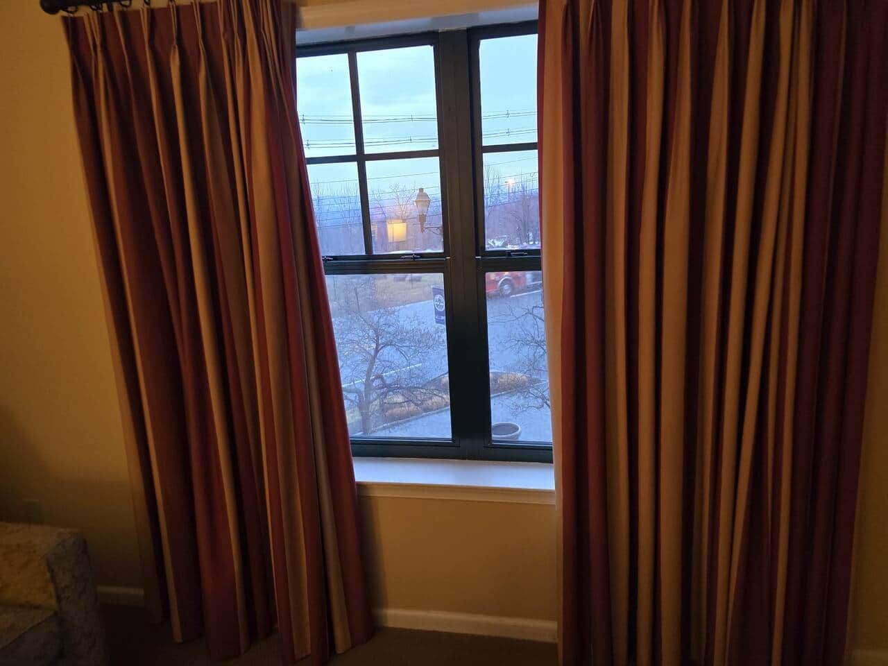 Une pièce avec une fenêtre, des rideaux et une vue sur un paysage enneigé.