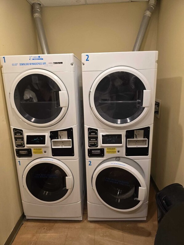Two stacked front-loading washing machines with control panels, labeled 1 and 2, in a laundry room.