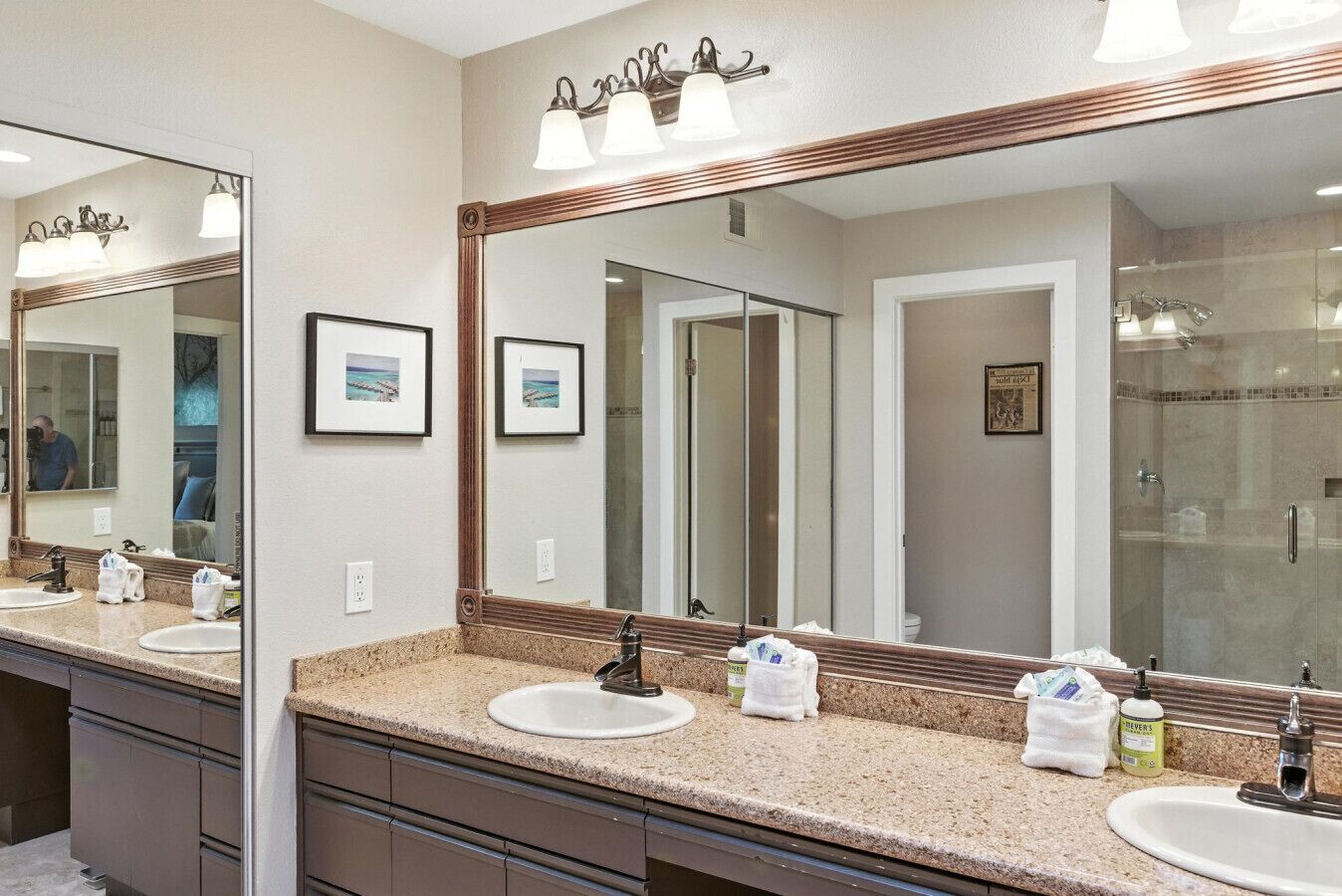 A bathroom with two sinks, a large mirror, and a shower.