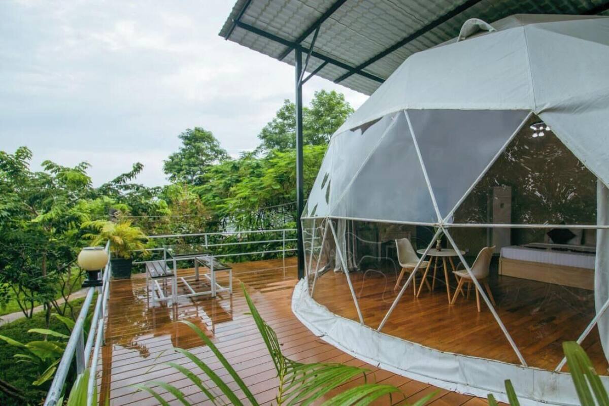 Une tente en forme de dôme dotée d’une terrasse en bois et de mobilier d’extérieur.