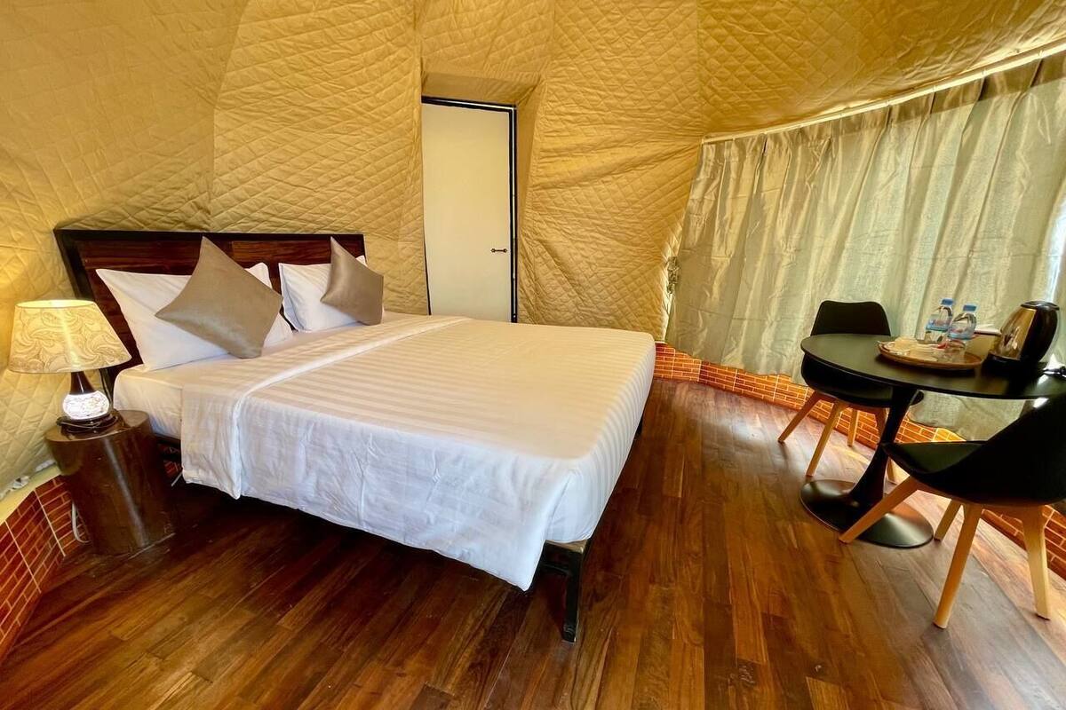 Une chambre à coucher comprenant un lit, une table de chevet, une lampe et une petite table avec des chaises.