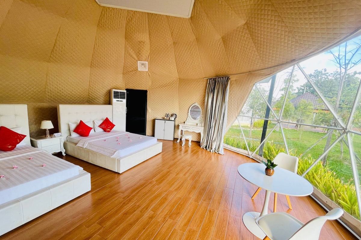 Une pièce spacieuse avec un grand lit, un bureau, une chaise et une vue dégagée sur l’extérieur grâce à une grande fenêtre.