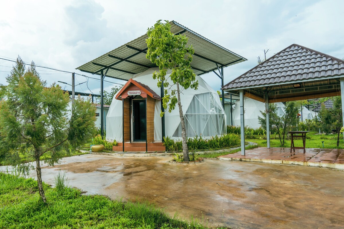 A building with a covered entrance, a small garden area, and a paved walkway.
