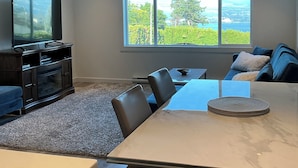 Un salon moderne doté d’une grande fenêtre, d’un téléviseur à écran plat, d’une table à manger et d’un canapé.