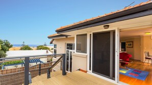 A balcony with a wooden floor and a metal railing, overlooking a residential area and the sea. - Scarborough Seaview on Brighton (Scarborough)