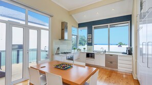 Una cocina moderna con ventanas amplias, un comedor y vista al mar.
