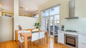 A modern kitchen with a dining area, large windows, and a view of the outside. - Scarborough Seaview on Brighton (Scarborough)