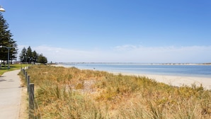 Un paseo marítimo con playa arenosa y dunas cubiertas de hierba.
