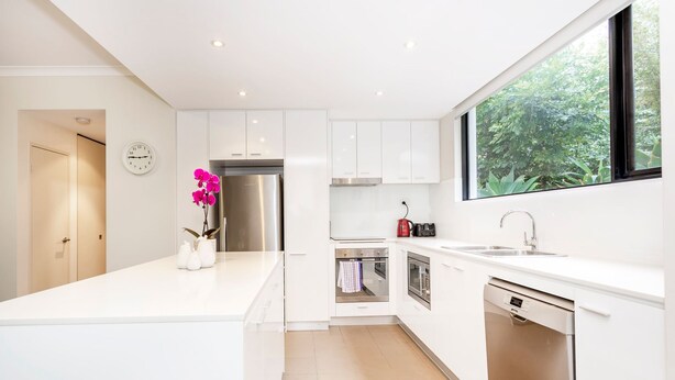 A modern kitchen with white cabinetry, stainless steel appliances, a built-in oven, and a dishwasher. - Subiaco Rooftop on Sheen (Subiaco)