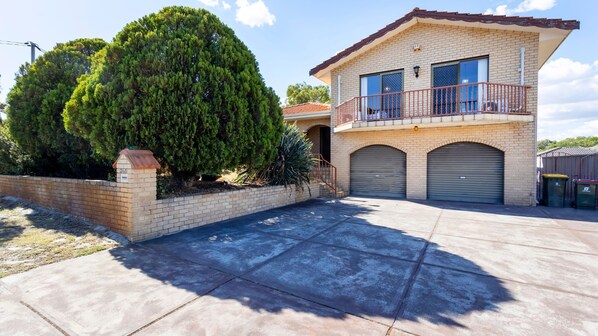 A two-story house with a balcony, a garage, and a well-maintained driveway. - Spacious Family Home situated in Dianella (Dianella)