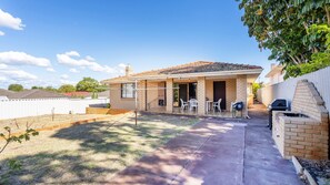A single-story house with a patio, a barbecue grill, and a small outdoor seating area. - Spacious Family Home situated in Dianella (Dianella)