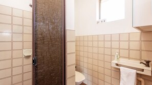A bathroom with beige tiles, a white sink, a mirror, and a toilet. - Spacious Family Home situated in Dianella (Dianella)