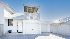 A modern two-story house with a garage, a covered outdoor area, and a large window. - Scarborough Villa on Mickey (Scarborough)