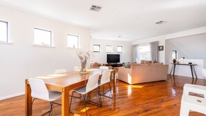 A spacious living area with a wooden dining table, white chairs, a beige sofa, and a TV. - Scarborough Villa on Mickey (Scarborough)