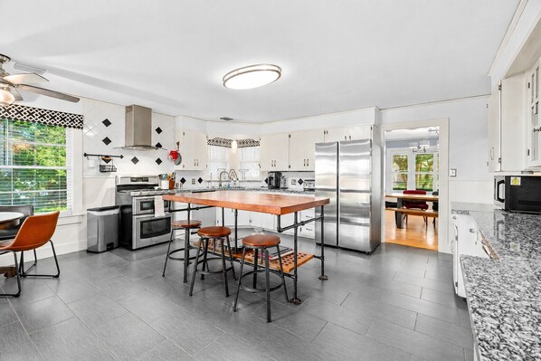 A modern kitchen with a central island, stainless steel appliances, and a dining area with bar stools.