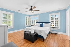 A bedroom with a bed, bedside tables, a bench, and a ceiling fan.