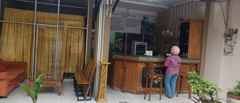 A reception area with a counter, a wooden bench, and a sign for a hotel.