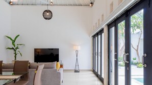 A modern living room with a sofa, chairs, a TV, and a floor lamp.