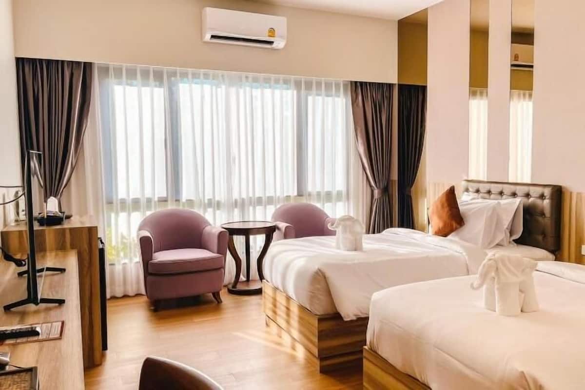 A hotel room with two beds, a desk, a chair, and a small table.