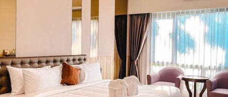 A hotel room with a large bed, a small round table, and two armchairs.