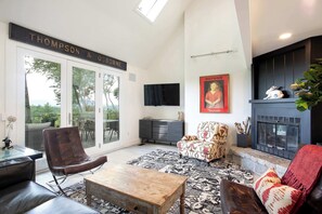 A living room with a fireplace, a television, and a sign reading "Thompson & Osborne." - Hilltop Escape with Views & Hot Tub (New Marlborough)