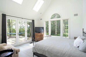 A bedroom with a large bed, a TV, and a sliding glass door leading to an outdoor area. - Hilltop Escape with Views & Hot Tub (New Marlborough)